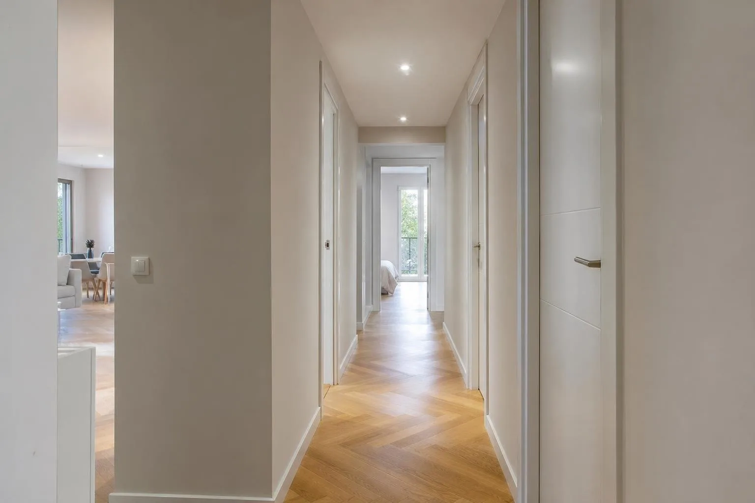 Pasillo reformado con parquet en espiga y puertas blancas