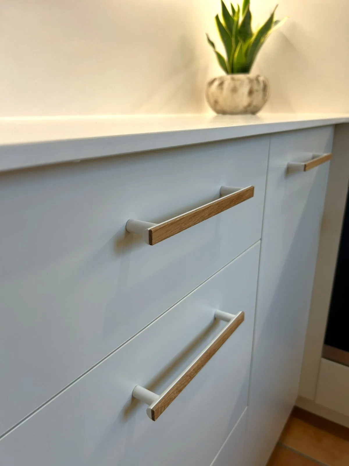 Detalle de cajones blancos de cocina con tiradores de madera