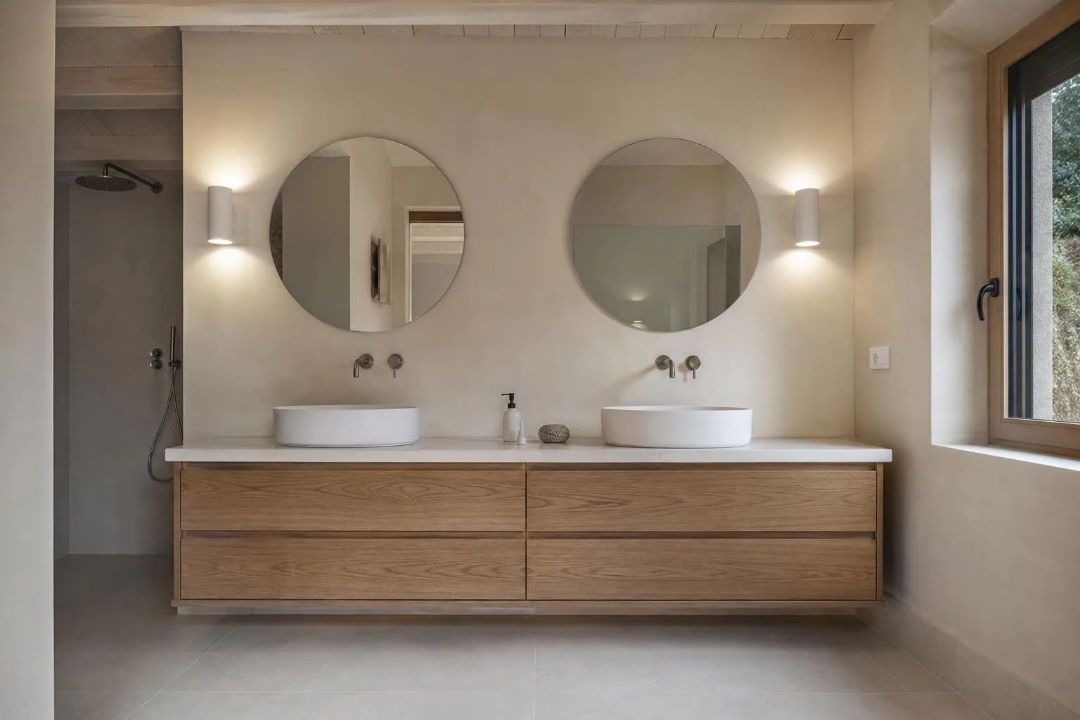 Baño con doble lavabo sobre mueble de roble y espejos redondos