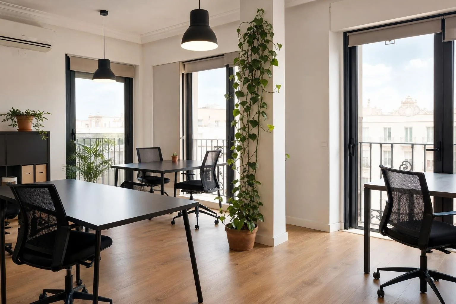 Espacio de trabajo compartido con mesas flexibles, plantas y grandes ventanales