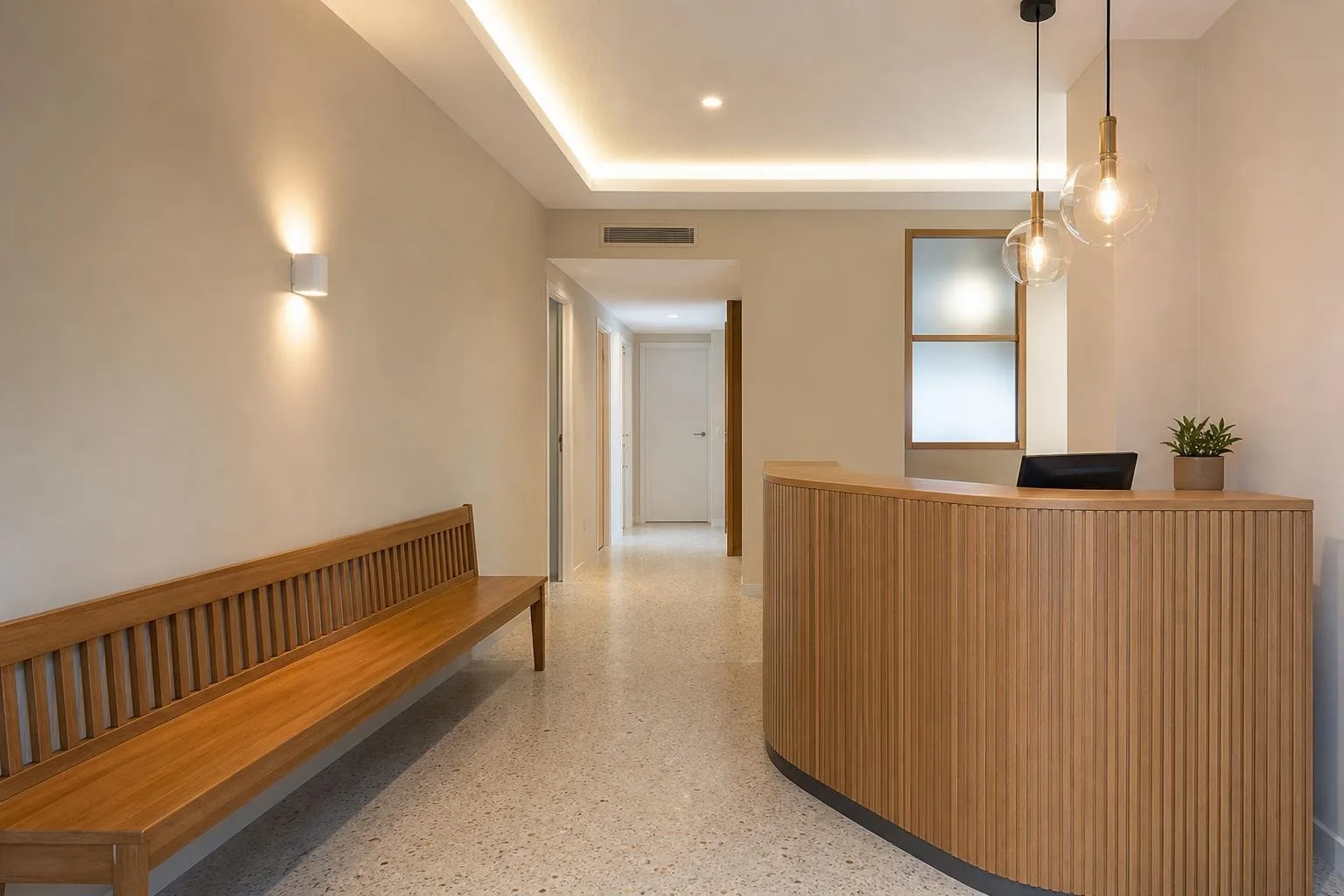 Sala de espera de un local reformado con mostrador de recepción y banco de madera